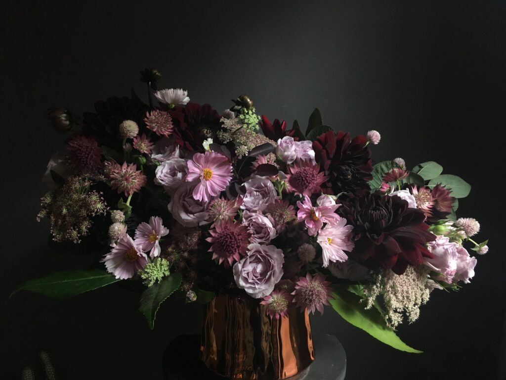 This captivating image showcases a meticulously arranged bouquet, blooming with deeper shades of burgundy and romantic shades of pink flowers.