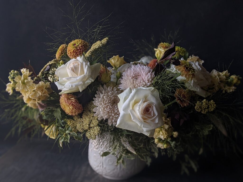 Classic, lush mixed flower arrangement in low ceramic vase.